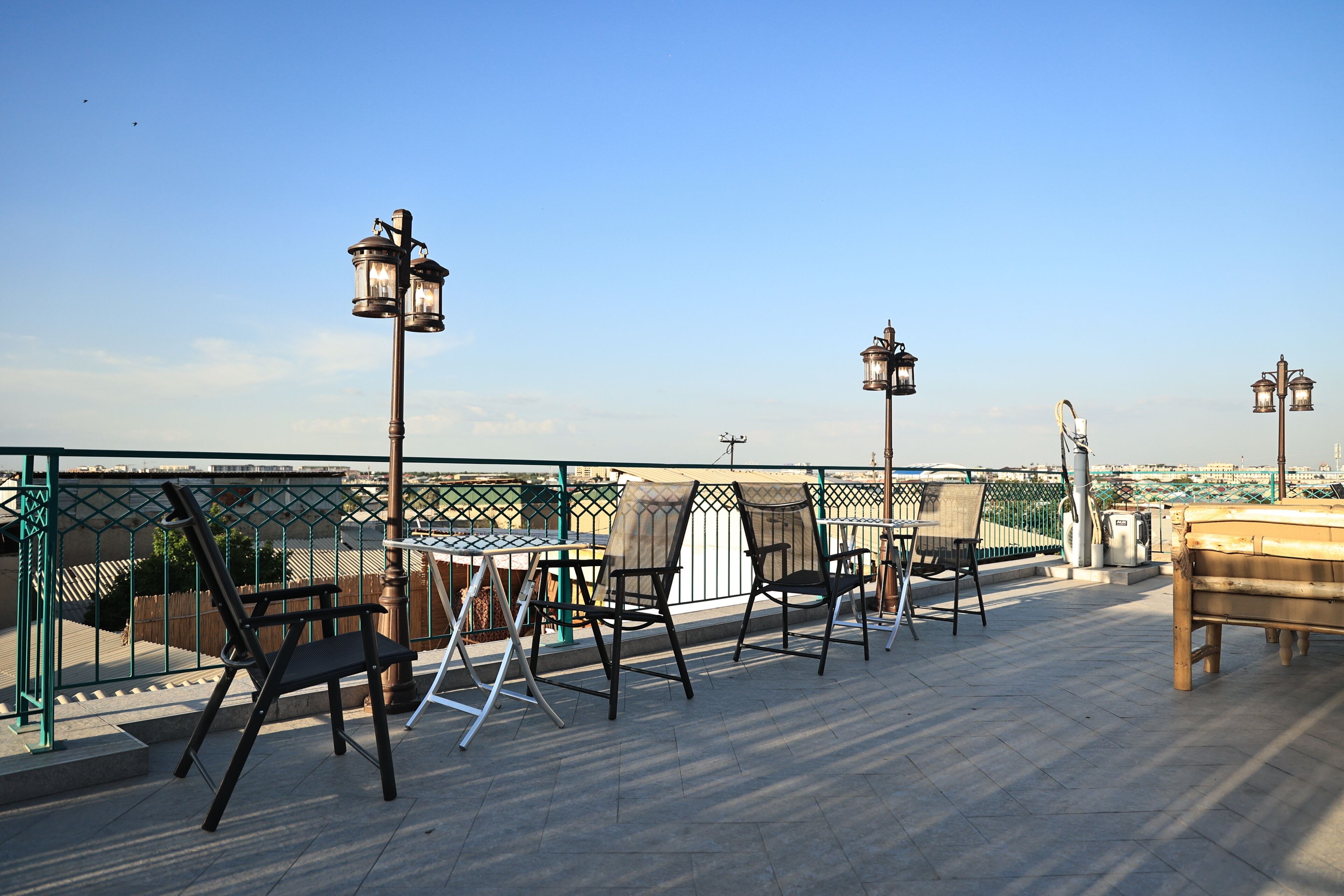 A rooftop terrace with outdoor seating, including tables and chairs, and decorative lanterns.