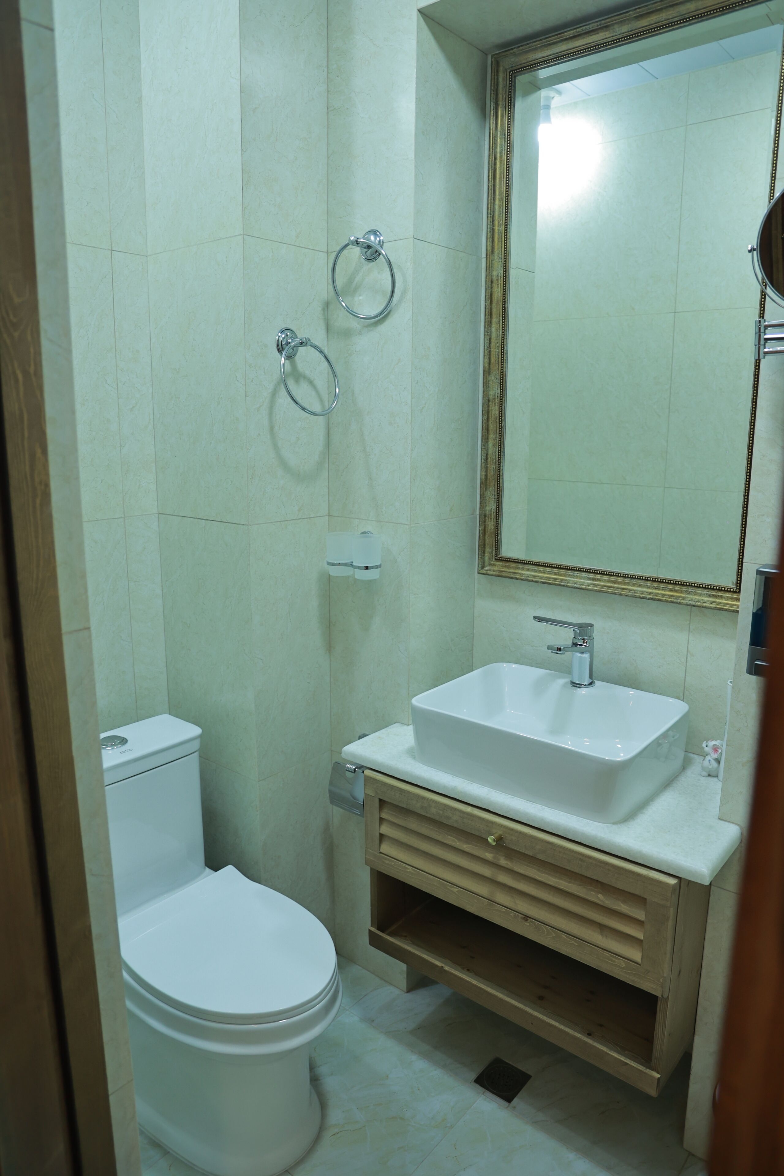 Ein Badezimmer mit Toilette, Waschbecken, Spiegel und Handtuchhalterungen.