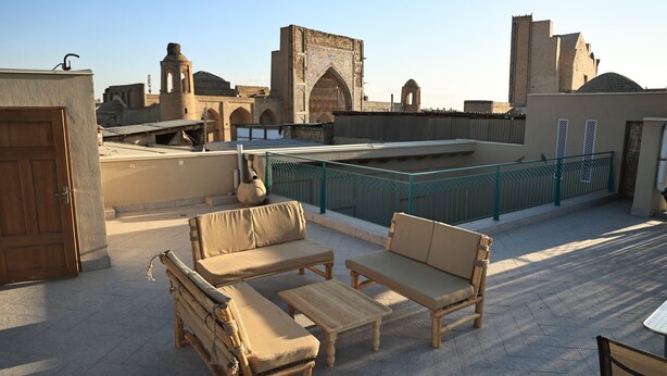 A rooftop terrace with outdoor furniture, a view of historic architecture, and a clear sky. - BAKOVUL HERITAGE  (Bukhara)