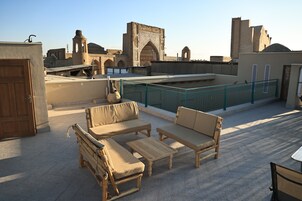 Una terraza en la azotea con mobiliario exterior, vistas a arquitectura histórica y cielo despejado.