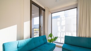 A modern living room with two teal sofas, a large sliding glass door, and a potted plant. - City Hideaway with Terrace in Antwerp (Antwerp)