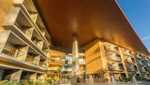 A multi-story hotel with a modern architectural design, featuring balconies and a central courtyard with a fountain. - Rioverde Living suites- Apartahotel (Antioquia)