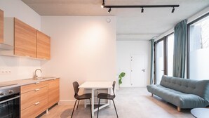 Una cocina moderna con armarios de madera, una mesa de comedor con sillas, un sofá y un ventanal con cortinas.