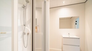 Un baño moderno con cabina de ducha de vidrio, un lavabo blanco y un espejo sobre él.