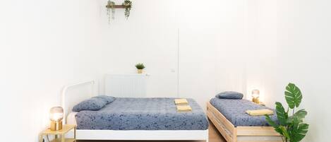 Ein Schlafzimmer mit zwei Betten, einem Heizkörper, einem Nachttisch mit Lampe und einer Zimmerpflanze.