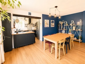 Eine moderne Küche mit einer zentralen Kochinsel, einem Essbereich mit Holztisch und -stühlen sowie einer Wand in Blautönen.