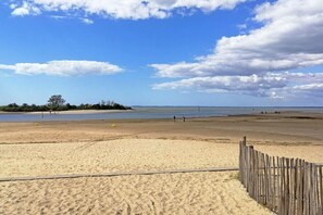 A sandy beach with a wooden fence, a clear sky, and a distant shoreline. - Cozy Villa with Spa - Beach Within Walking Distance - Gujan-La Hume (Gujan-Mestras)