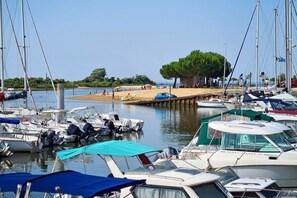 A marina with boats docked, a sandy beach, and a tree in the background. - Cozy Villa with Spa - Beach Within Walking Distance - Gujan-La Hume (Gujan-Mestras)