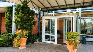 A hotel entrance with a covered patio, glass doors, and potted plants. - Braunschweig Hotel by Belvilla  Standard Twin Room (Braunschweig)