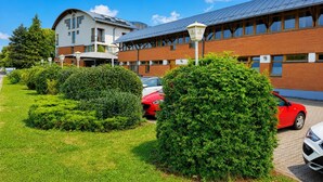 A building with a brick facade, a curved roof, and a parking area with cars. - Braunschweig Hotel by Belvilla  Standard Twin Room (Braunschweig)