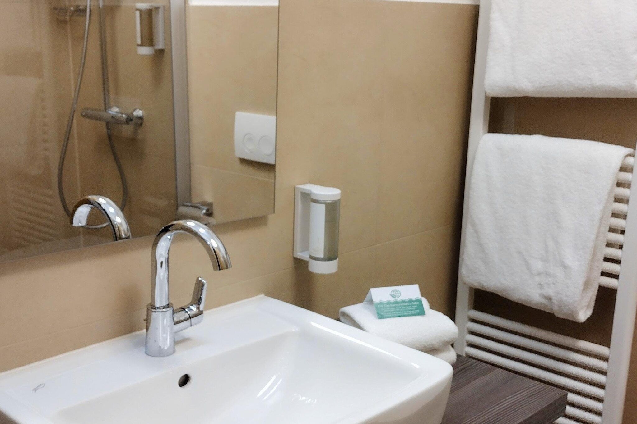Ein Badezimmer mit Waschbecken, Spiegel, Handtuchhalter und Seifenspender.