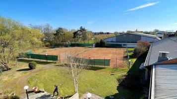 Ein Tennisplatz, umgeben von Bäumen und Gebäuden.