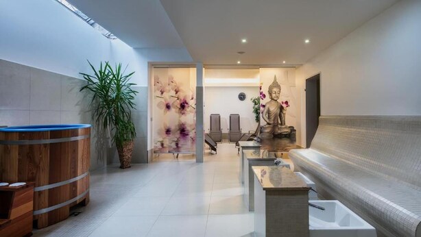 Ein moderner Wellnessbereich mit Holzauna, Buddha-Statue und einer Rezeption.