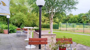 Un patio al aire libre con bancos, mesas y plantas en macetas.