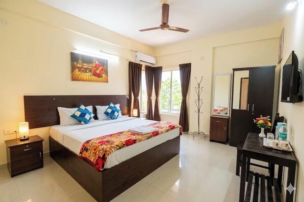 A hotel room with a bed, bedside table, wardrobe, and a ceiling fan.