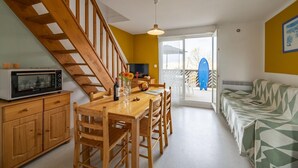 Een keuken met houten kastjes, een eettafel en een trap.