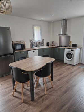 Eine moderne Küche mit Essbereich, inklusive Kühlschrank, Mikrowelle, Spüle und Waschmaschine.