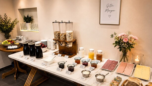 Un bufé de desayuno con diversas opciones de comida y bebidas, como frutas, cereales y productos lácteos.
