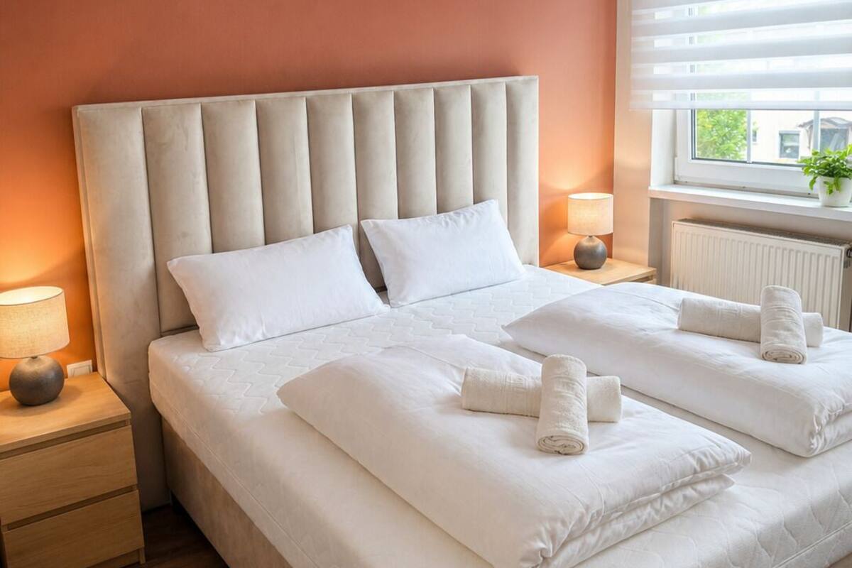 A double bed with a tufted headboard, white bedding, and two bedside tables with lamps.