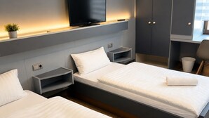 Una habitación de hotel moderna con dos camas, un televisor y una pequeña planta.