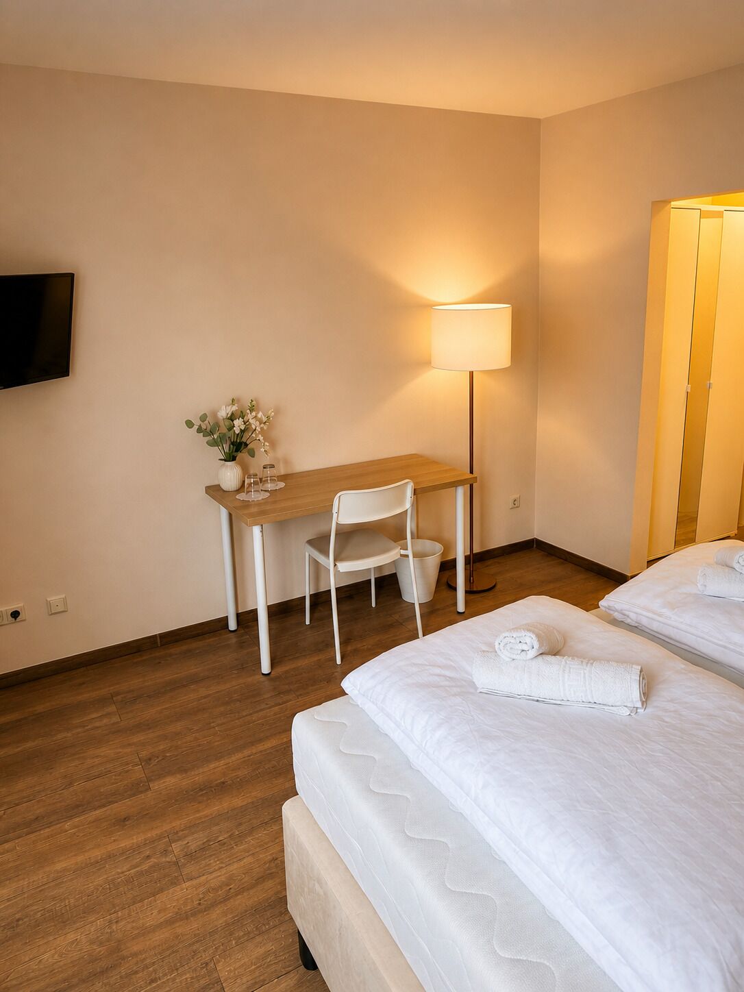 Ein Hotelzimmer mit einem Bett, einem Schreibtisch, einem Stuhl, einem Fernseher und einer Lampe.