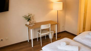 Ein Hotelzimmer mit einem Bett, einem Schreibtisch, einem Stuhl, einem Fernseher und einer Lampe.