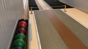 Een bowlingbaan met banen, een bollembalhouder en een potplant.