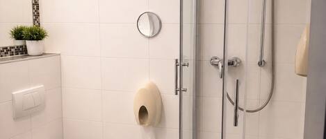 Un baño moderno con ducha de vidrio, inodoro, lavamanos y espejo.