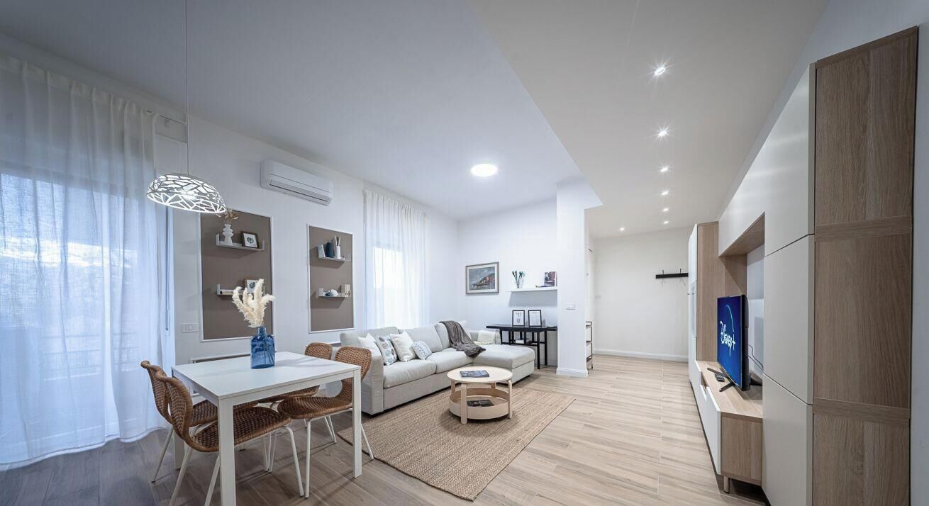 A modern living room with a dining area, a sofa, a TV, and a bookshelf.