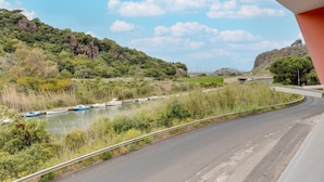 A curved road with a river, boats, and a bridge in the background. - Apartment with sea view terrace and air conditioning (Castelsardo)