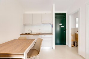 Eine moderne Küche mit weißen Schränken, einem Holzespeisetisch und einer grünen Tür im Hintergrund.