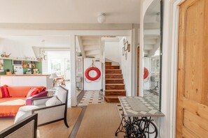 Ein gemütliches Wohnzimmer mit einer Couch, einem Tisch und einer Treppe, die in einen anderen Raum führt.