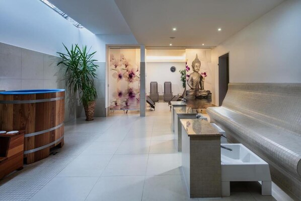Ein moderner Wellnessbereich mit Holzauna, Buddha-Statue und einer Rezeption.
