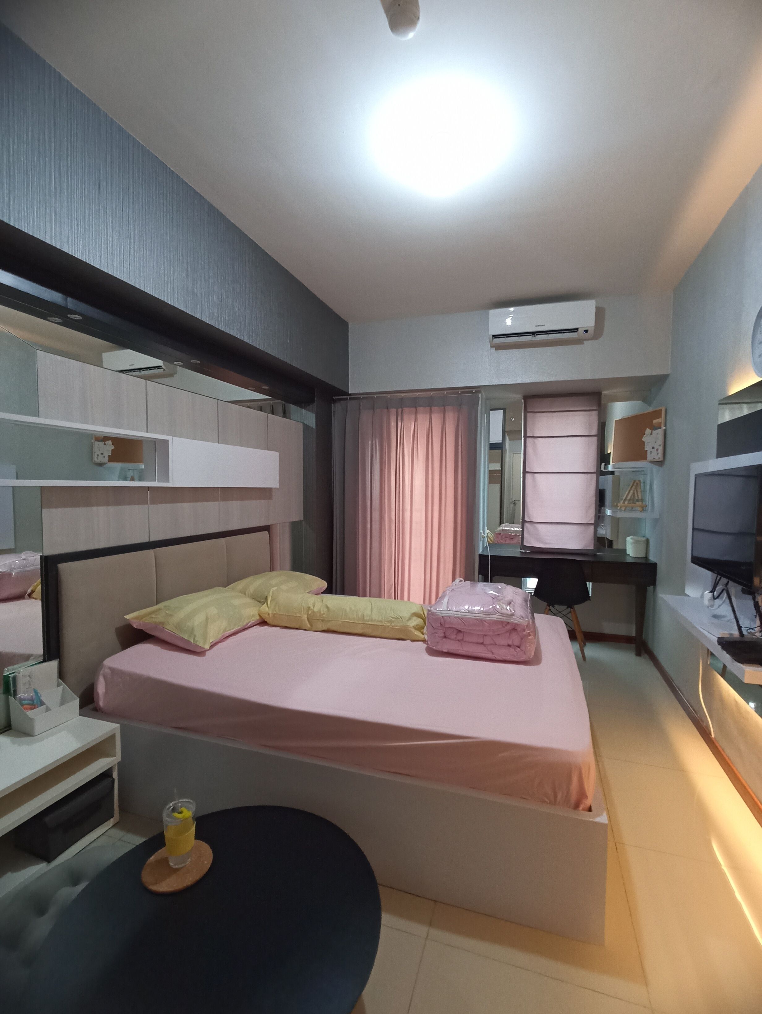 Slaapkamer met een bed, nachtkastjes, een bureau, een stoel, een airconditioning en een televisie.
