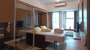 Una habitación de hotel moderna con una cama, una mesa redonda, un espejo y un equipo de aire acondicionado.