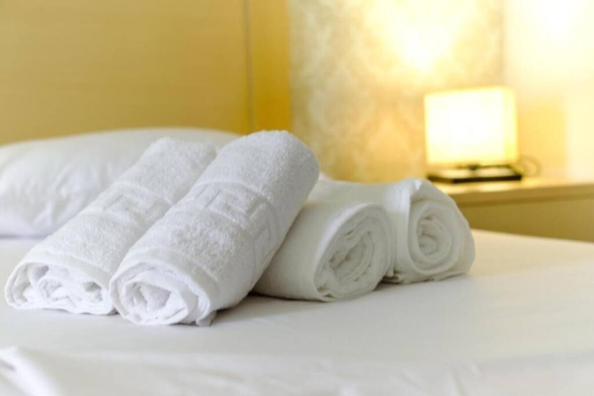 A bed with neatly folded white towels and a bedside lamp.