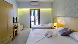 A hotel room with two beds, a desk with a television, a wardrobe, and a door leading outside. - Aphrodite Hotel Syros  (Syros)