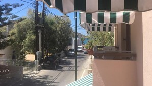 A street view with a building featuring a striped awning, a parked car, and a street lamp. - Aphrodite Hotel Syros  (Syros)