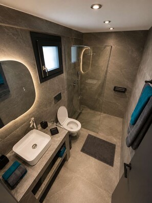 Un baño moderno con lavamanos, inodoro y ducha.
