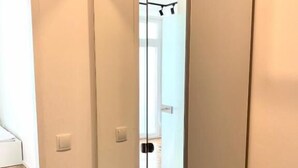 Una habitación con una puerta corredera que da a un baño, una encimera negra y un suelo de tonos claros.