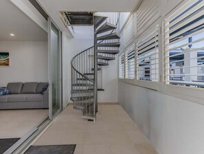 Ein modernes Interieur mit einer Wendeltreppe, einer Couch und einem Fenster mit Jalousien.