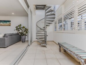 Ein modernes Interieur mit einer Wendeltreppe, einem grauen Sofa, einem Blumentopf und einer Bank.