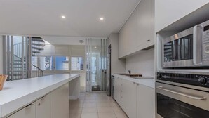 A modern kitchen with white cabinetry, a stainless steel oven, and a glass door refrigerator. - Coastal Luxe Rooftop Escape - Paradiso 345 (Tweed)