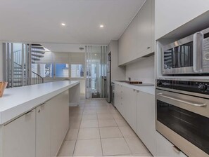 Eine moderne Küche mit weißen Schränken, einem Edelstahlbackofen und einem Kühlschrank mit Glastür.