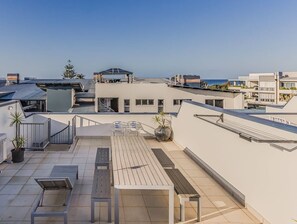 A rooftop terrace with seating, potted plants, and a clear view of the sea. - Coastal Luxe Rooftop Escape - Paradiso 345 (Tweed)