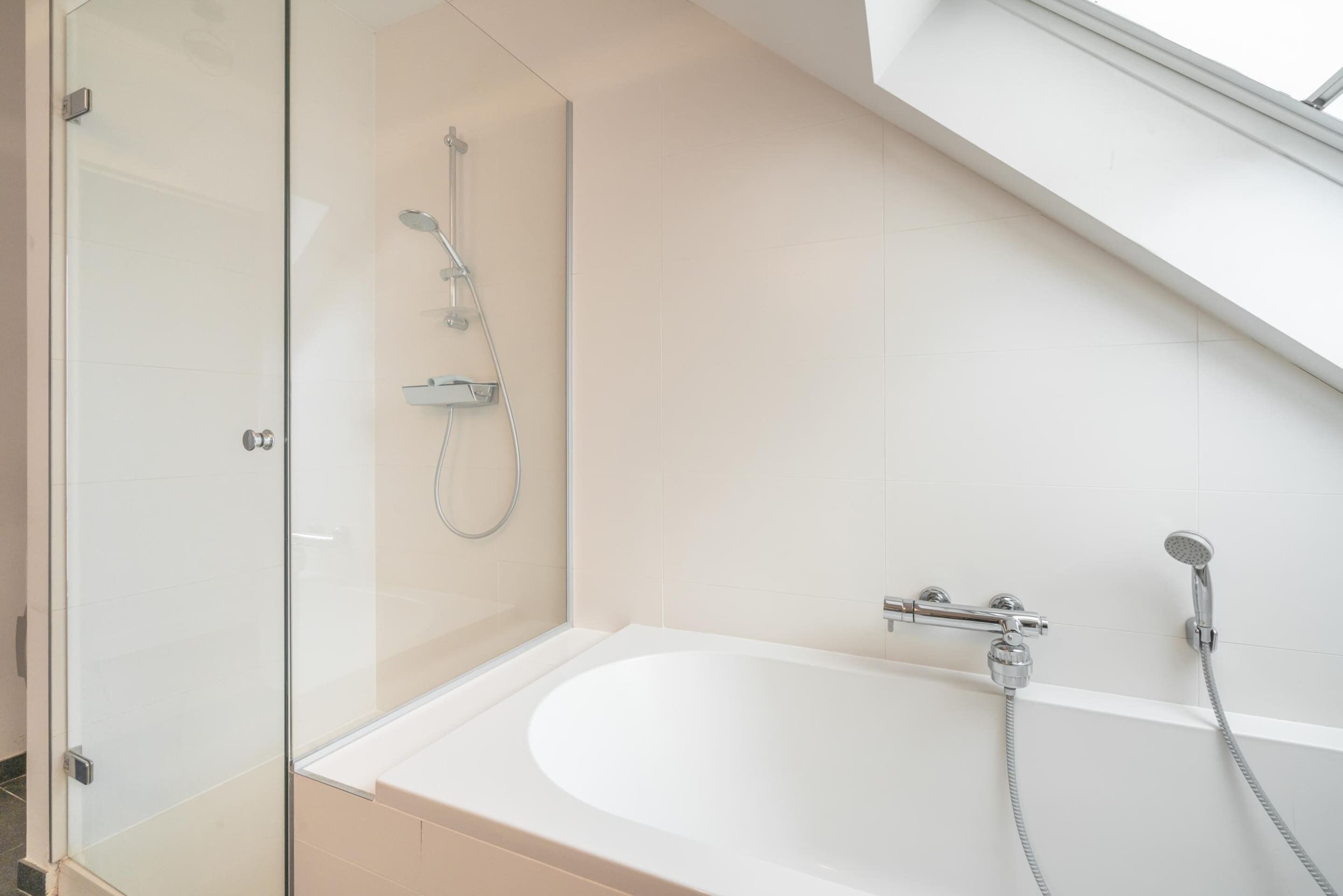 Un baño moderno con cabina de ducha de vidrio, una bañera independiente y un cabezal de ducha.