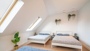 Ein Schlafzimmer mit zwei Betten, einem Oberlicht und hängenden Pflanzen.