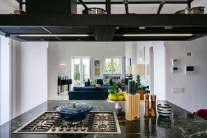 Eine moderne Küche mit einem Gasherd, einer Marmorarbeitsplatte und einem Essbereich mit einer Couch und Dekorationselementen.