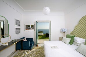 Ein Schlafzimmer mit Bett, Schreibtisch, Stuhl, Spiegel und Meerblick.