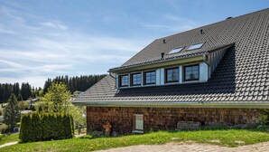 Ein Haus mit geneigtem Dach, einer kleinen Veranda und einem gepflasterten Auffahrt.